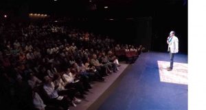 Clean corporate comedian Shaun Eli on stage at the Emelin Theatre in Mamaroneck, NY as the audience applauds