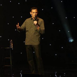 Comedian Andy Hendrickson on stage holding a microphone