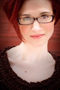 Book or hire edgy stand-up comedian Adrienne Iapalucci (her headshot, with Adrienne in glasses)